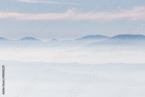 Fog filling a valley, with layers of mountains and hills and various shades of blue