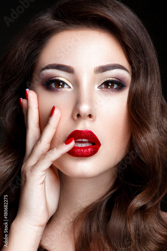 Fashion woman portrait on black background with red shiny lips and red nails.