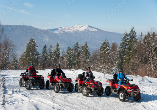Four ATV riders on off-road quad bikes at top of the mountain in winter