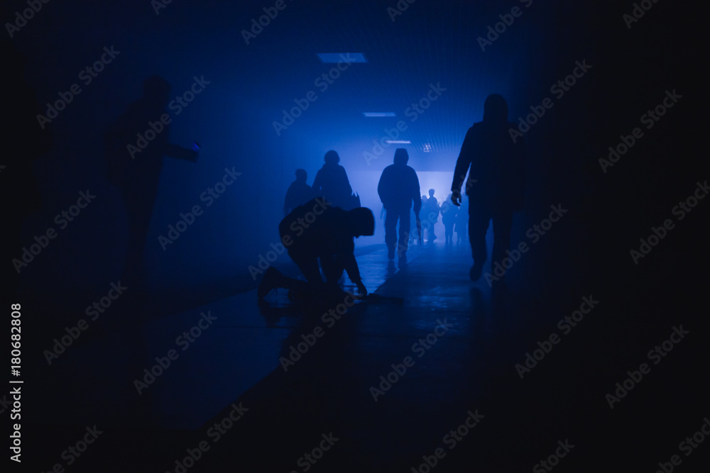 silhouette of a fallen man walking in a tunnel in a smoke against a background of bright light