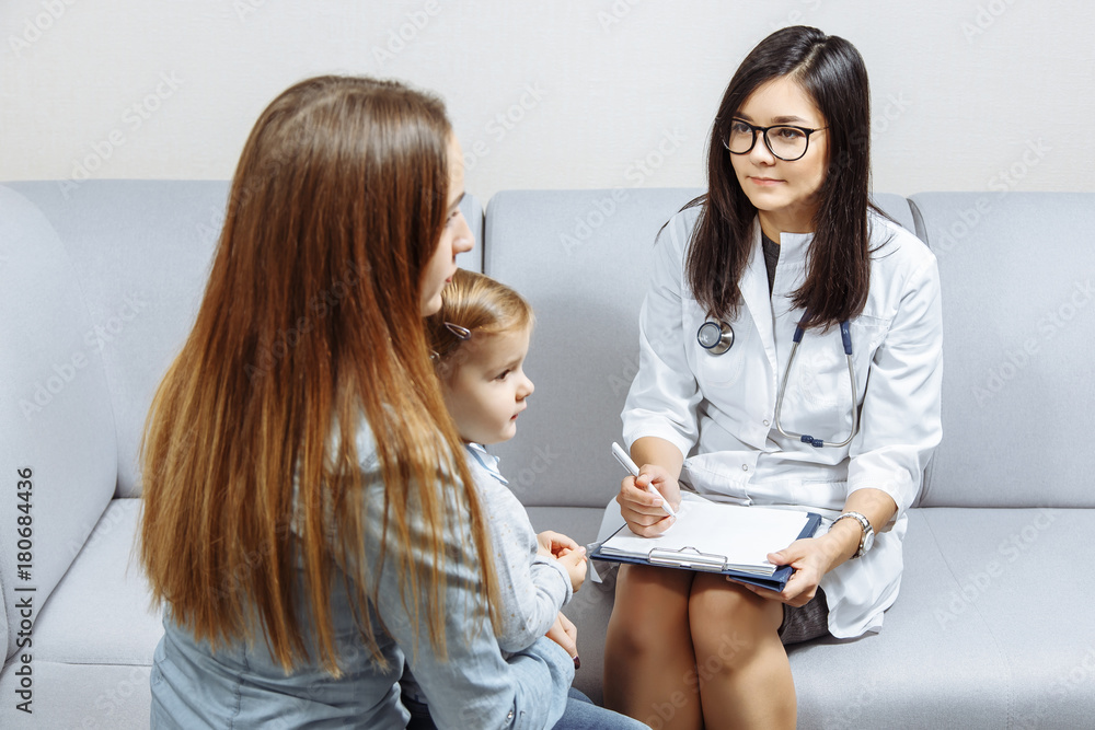 Little girl and her young mother are consulting with pediatrician in his office Little girl and her young mother are consulting with pediatrician in his office