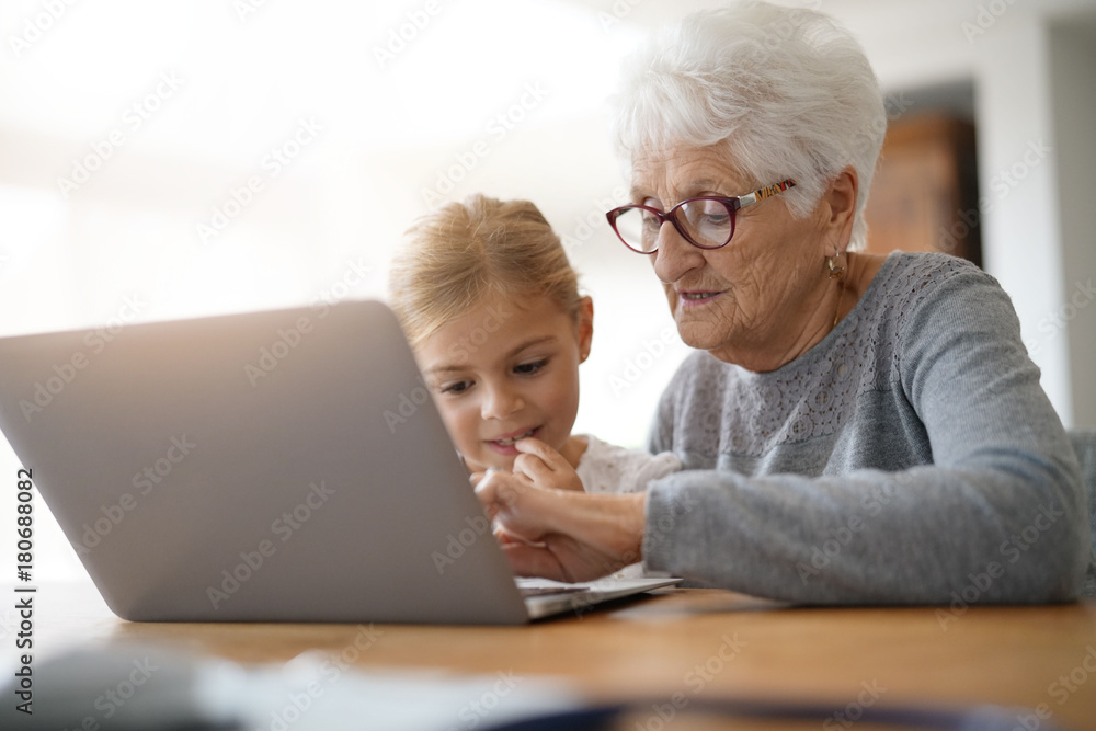 Little girl with grandmother using laptop computer