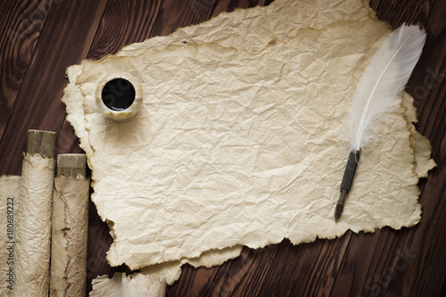 white feather and ancient scroll on brown plank