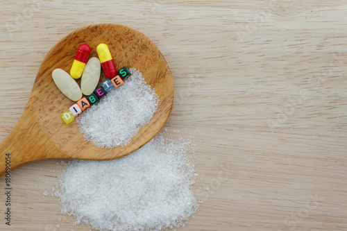 Medicine and the word Diabetes and sugar in spatula on wooden background