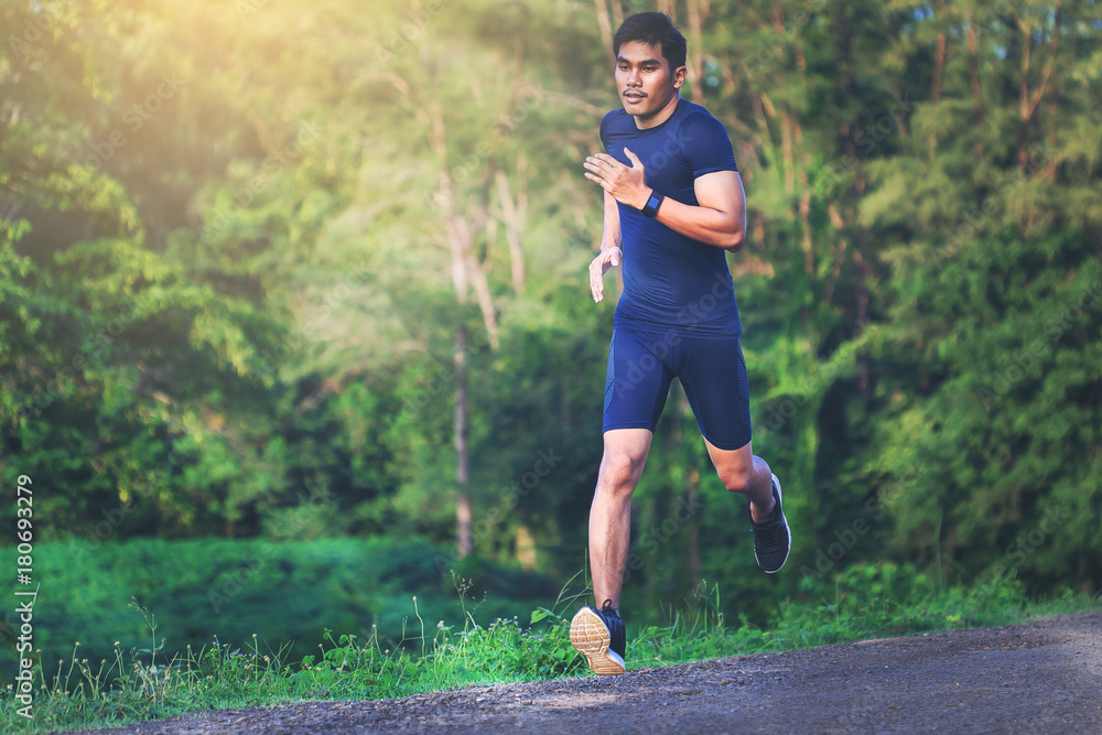 Man running sprinting on road. Fit male fitness runner during outdoor workout.