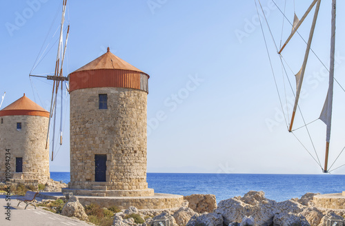 Red roof old windmill on coast with blue cloudy sky and sea in the background