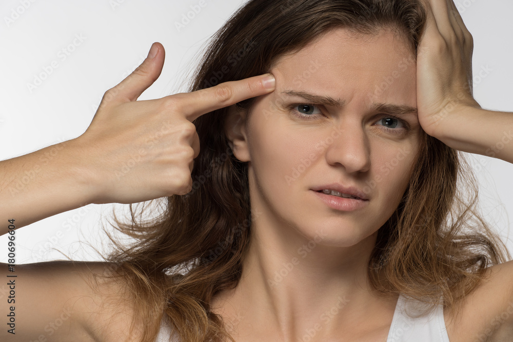 Obraz premium Young girl experiencing headache or depression and mourned over white background