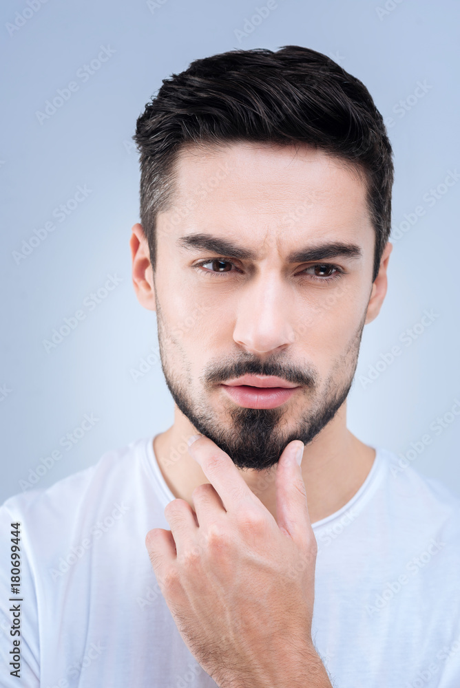 Careful consideration. Calm clever qualified specialist standing and touching his chin while thinking about his new interesting project Careful consideration. Calm clever qualified specialist standing and touching his chin while thinking about his new interesting project