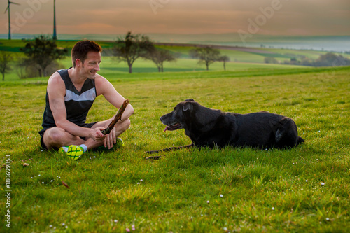 young man playing with a dog on the field © Pavel