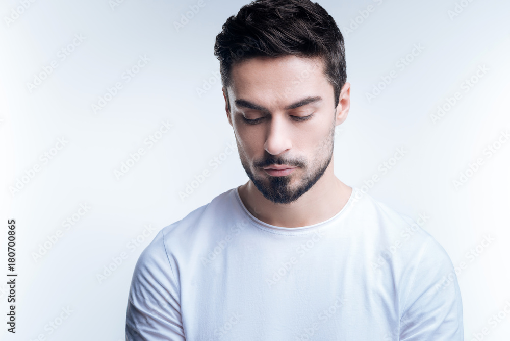 Obraz premium Looking down. Handsome young calm man looking down at his beautiful fashionable new shoes while standing against the blue background
