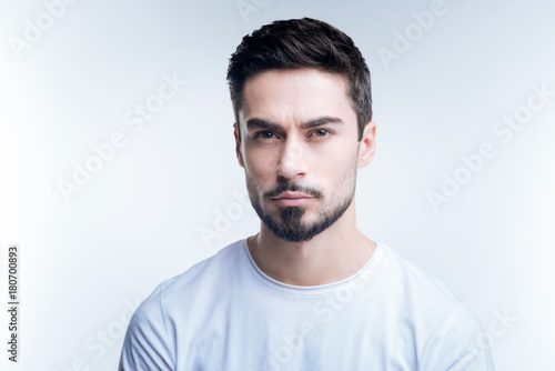 Strict person. Serious demanding young teacher looking strict while standing against the blue background and waiting for his students © zinkevych