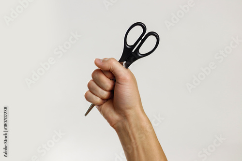 Male hands holding black scissors. Isolated on gray background. Closeup