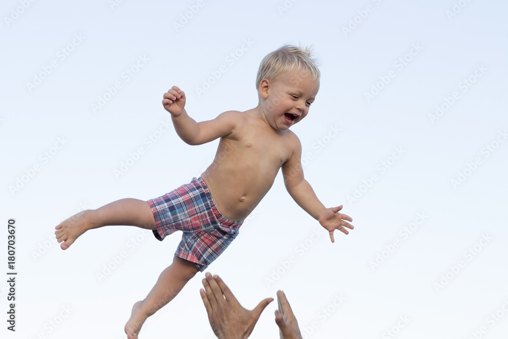 Cute happy smiling toddler having fun on the sea. Father throwes up his little son Cute happy smiling toddler having fun on the sea. Father throwes up his little son