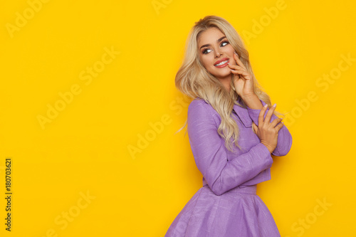 Beuatiful Blond Woman In Violet Costume Is Smiling And Looking At Yellow Copy Space