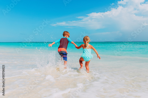 little boy and girl run play with water at beach