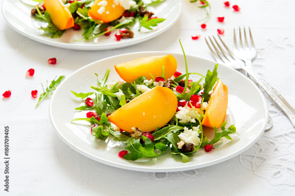 Fresh autumn salad with persimmon, arugula, cheese and pomegranate seeds on white table cloth. Space for copy Fresh autumn salad with persimmon, arugula, cheese and pomegranate seeds on white table cloth. Space for copy