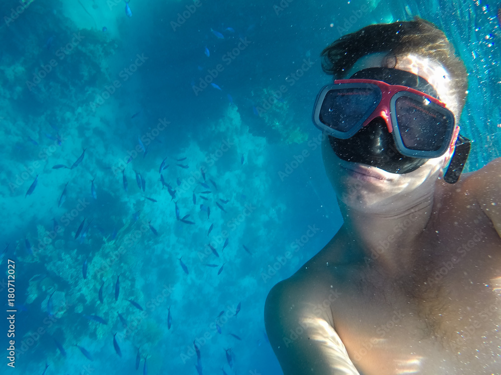 A man with an underwater mask swims near the corals in the Red Sea, engaged in diving