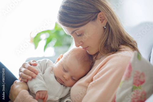 Young mother, holding tenderly her newborn baby boy