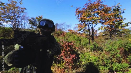 Soldier on a mission. Soldier with AK rifle seeking for enemies. Old rusty military ruins on background. photo