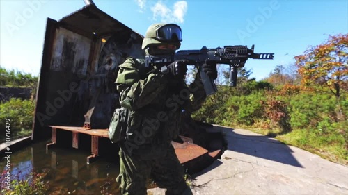 Soldier with AK rifle and modern uniform on old AAA post. photo