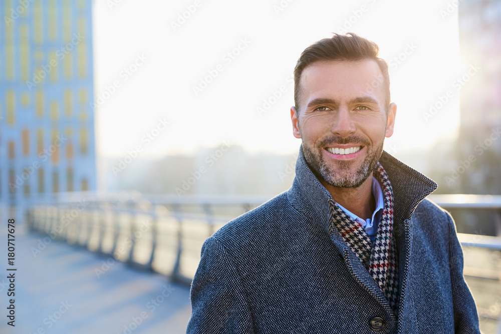 Fototapeta premium Portrait of happy businessman standing outdoors during sunny winter day
