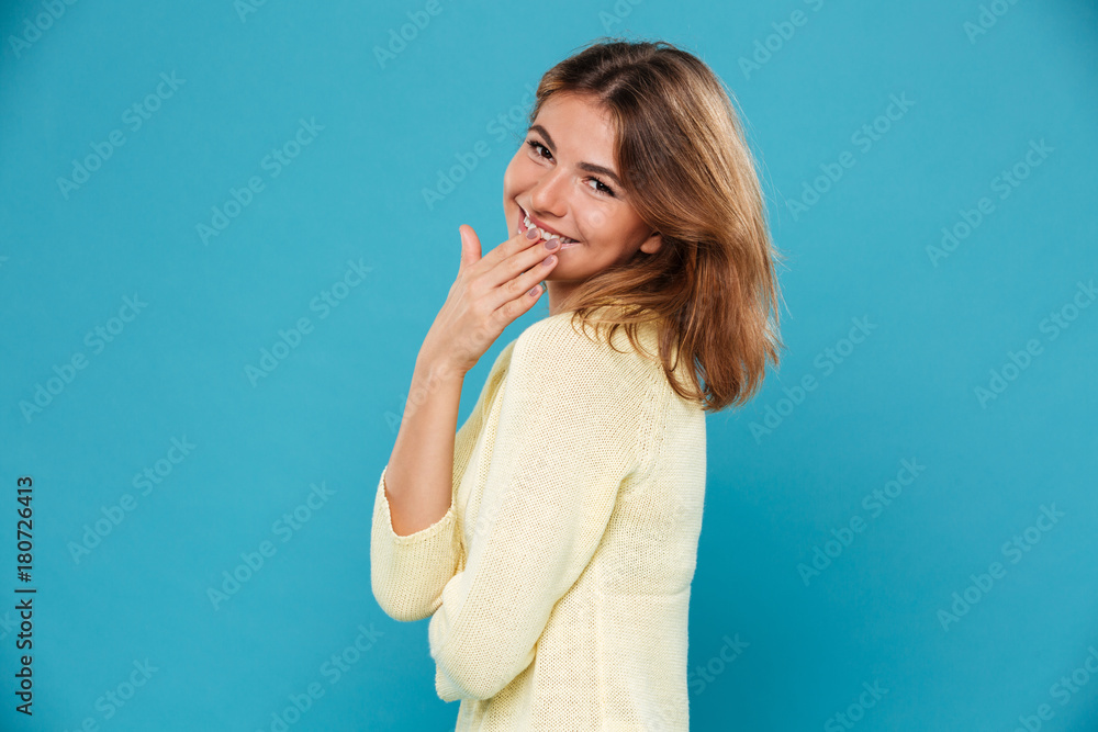 Side view of Smiling woman in sweater covering her mouth Side view of Smiling woman in sweater covering her mouth