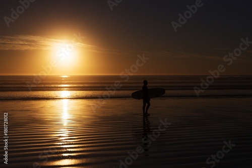 surfer with surfboard silhouette at the sunset beach