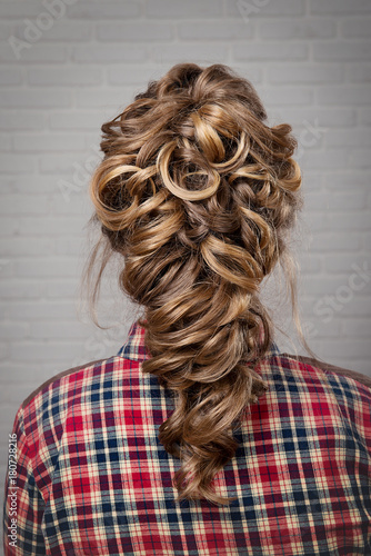 Women's hairstyle halo braid on the hair of the brown rear view on a light background