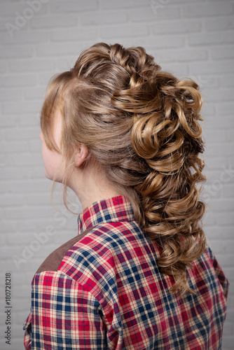 Women's hairstyle halo braid on the hair of the brown-haired rear view of the head turning left on a light background