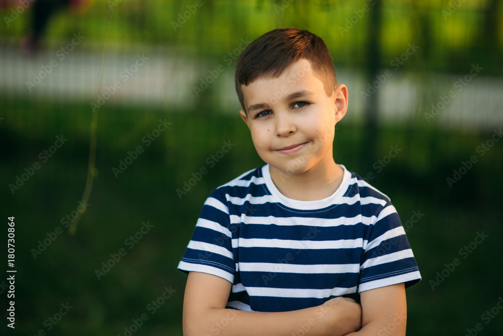 A little boy in a striped T-shirt is playing on the playground, Swing on a swing. Child is smiling and cheering A little boy in a striped T-shirt is playing on the playground, Swing on a swing. Child is smiling and cheering