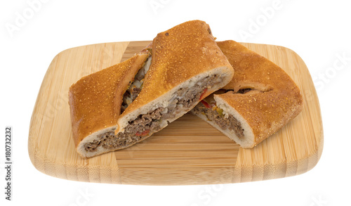 Fényképezés Two slices of a baked steak stromboli on a wood cutting board isolated on a white background