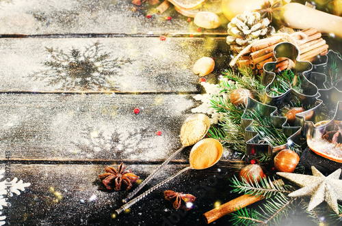 Christmas background - cones, fir tree, dough, flour, rolling pin, eggs, egg yolksover, spices, dry oranges, old dark wood background. Top view, copy space, snow, bokeh.