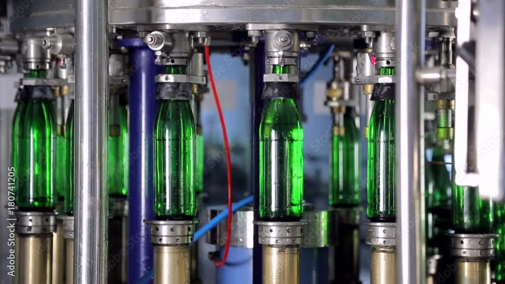 Line of water production. Green glass bottles move automatically along the lines of production, and fill with water