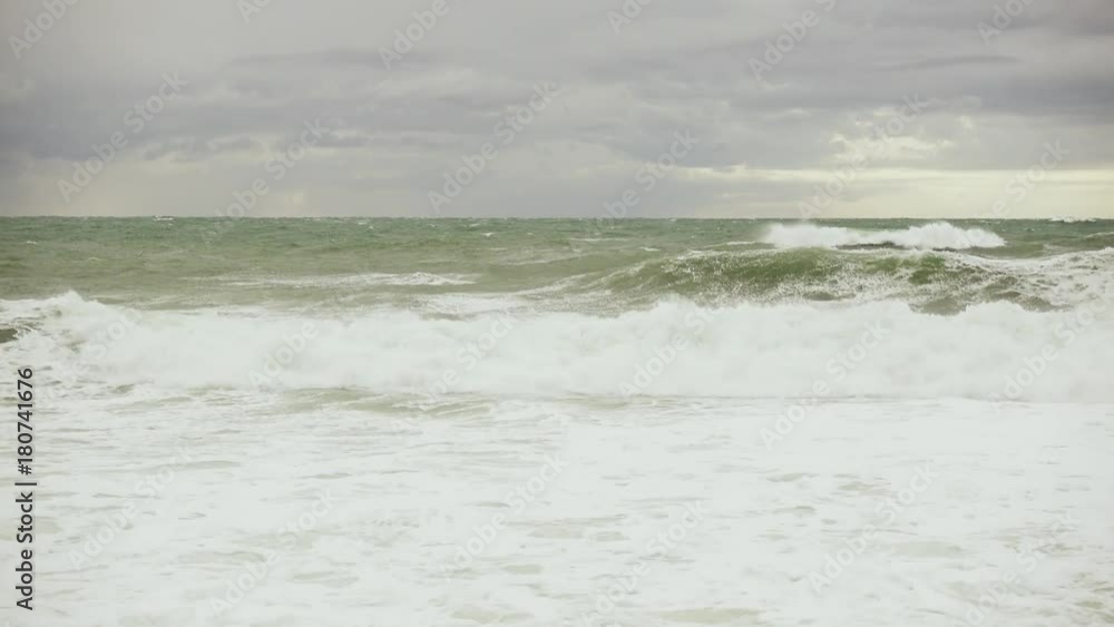The stormy ocean under gray clouds on the horizon glimpses the sunlight The stormy ocean under gray clouds on the horizon glimpses the sunlight