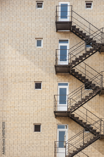 Fire Escape Stairs on the building. Construction with windows, walls of brickwork. Vertical orientation