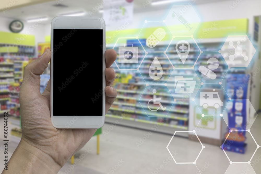 Hand holding smartphone with black blank screen over blurred pharmacy interior background with modern medical and health care interface. for product display montage