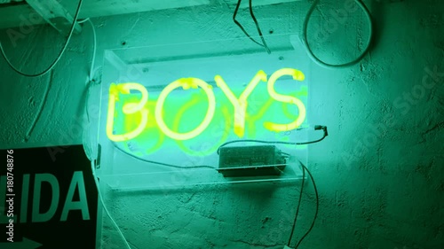 Hand held shot of huge neon sign glowing in dark of word boys, representing direction to bathroom or symbol of underground culture in cafe, bar or art gallery, vintage retro effect photo