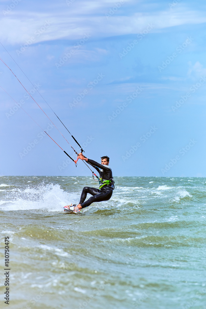 Man riding a kite surfing on the waves in the summer.