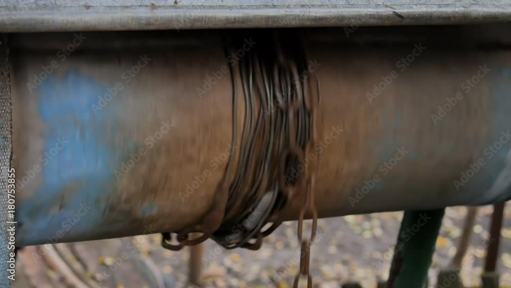 Man drops chain with bucket into rustic well to draw water. Dirty water. Man drops chain with bucket into rustic well to draw water. Dirty water.