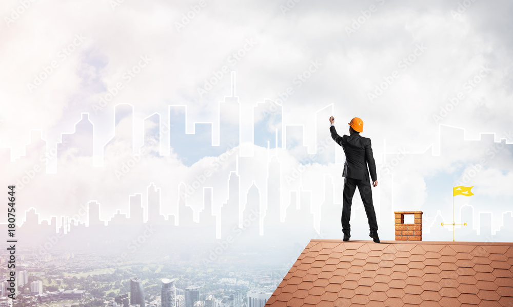 Man architect draw silhouette of modern city on blue sky. Mixed media