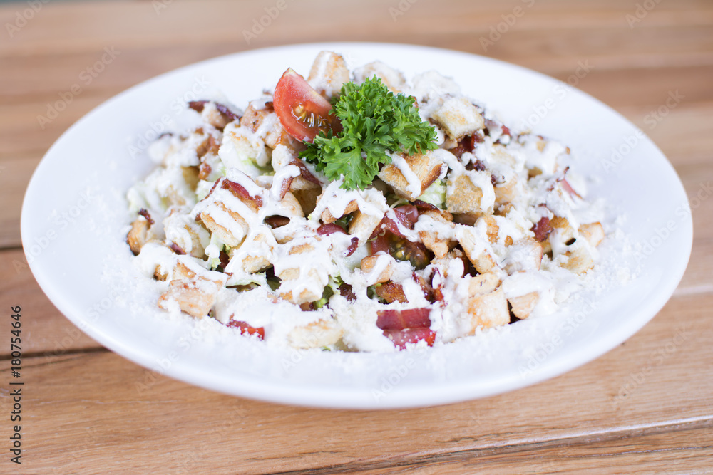 Healthy grilled red meat salad with cheese and croutons. Bacon and lettuce slices in a white plate on a wooden table. Healthy grilled red meat salad with cheese and croutons. Bacon and lettuce slices in a white plate on a wooden table.