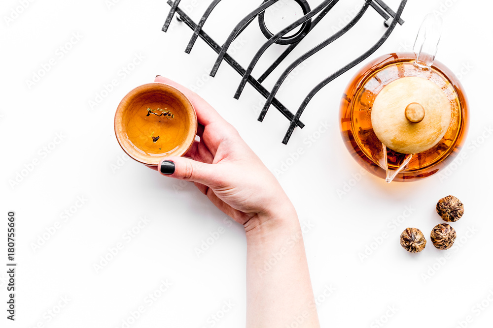 Tea ceremony concept. Hand takes cup near tea pot on white background top view copyspace