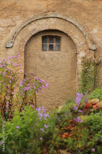 Plastered wall with arch and window in fron of defocused blossoms