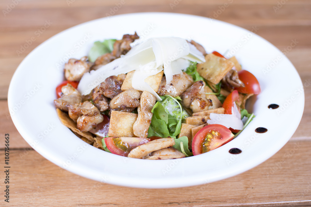 Salad with tomato, mozzarella, and meat on white plate close up. Served restaurant table. Delicious meal at a luxury restaurant. Salad with tomato, mozzarella, and meat on white plate close up. Served restaurant table. Delicious meal at a luxury restaurant.