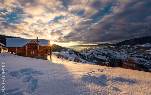 Tableau sur toile wooden chalet in village outskirts at sunrise