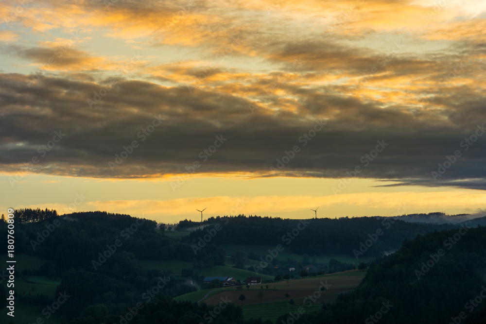 Romantic colorful sunset over black forest near Freiburg with orange sky and misty atmosphere