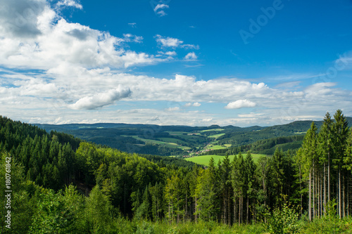 Endless wide scenic view on black forest landscape with blue sky and small village far away