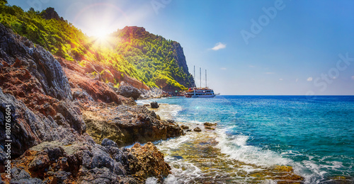 Tropical rocky beach on sunny summer day in Alanya, Turkey. Sea and mountains landscape with waves. Lagoon bay. Panoramic view on paradise coastline. Summer vacation nature. Adventure and travel. photo