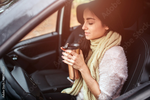 Woman holding disposable cup of coffee in car