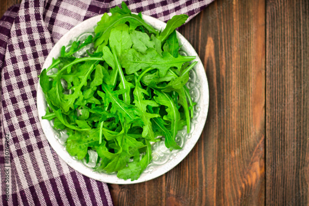 Fresh juicy leaves of arugula on a brown wooden table. Fresh juicy leaves of arugula on a brown wooden table.
